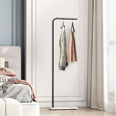 two towels are hanging on a coat rack in the corner of a room with a white couch