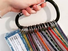 a person holding a metal ring with several different colored papers in it's holder