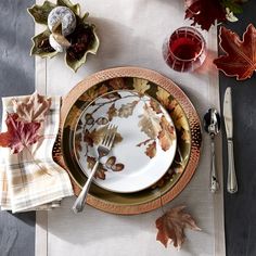 a place setting with autumn leaves and silverware