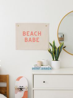 a bedroom with a skateboard, mirror and plant on the dresser next to it