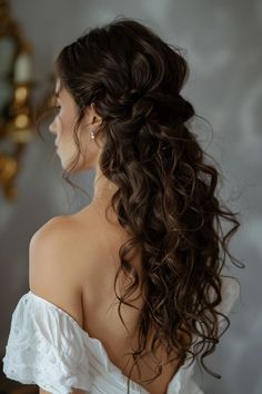 the back of a woman's head with long curly hair in a white dress