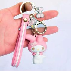 a pink hello kitty keychain is being held by a person's hand