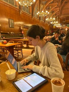 a woman sitting at a table using a laptop computer