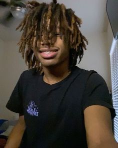 a young man with dreadlocks is smiling for the camera