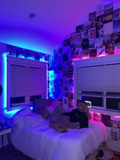 two people laying on a bed in a room with blue lights and pictures all over the walls