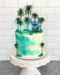 a cake with blue frosting and palm trees on top