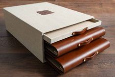 three brown leather cases are stacked on top of each other, with one opened and the other closed