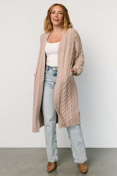 Staple layering piece for fall and winter fashion Soft taupe color Knit material has slight stretch Chunky cable knit pattern throughout Open cardigan style Oversized fit, we recommend sizing down Ribbing at sleeve cuffs and hem 60% Cotton, 40% Acrylic Marianne is 5'6, cup size 34D, size 6 and wearing size XS