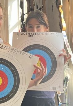 two girls are holding up archery target signs