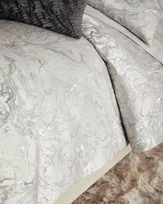 the comforter is made up with white and gray marbled sheets, pillows, and blankets