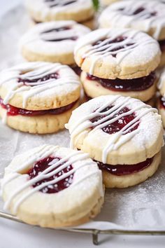 some cookies with icing and jelly are on a silver platter, ready to be eaten