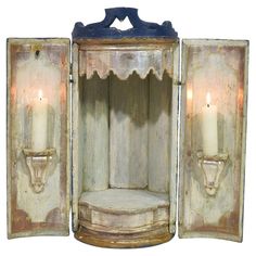 an old wooden cabinet with two candles in it