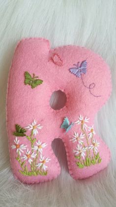 a pink felt letter decorated with flowers and butterflies