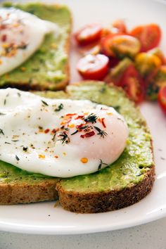 avocado toast with poached eggs on top and tomatoes in the background