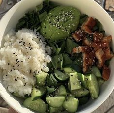 a white bowl filled with rice, cucumbers and other vegetables next to meat