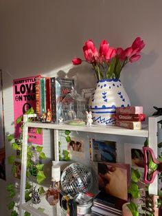 a shelf filled with books and vases on top of it