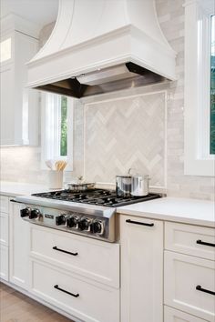 a stove top oven sitting inside of a kitchen next to white cabinets and counter tops