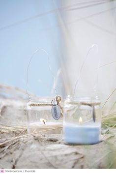 two jars with candles are sitting on the ground next to each other and one has a tag hanging from it