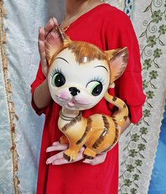 a woman in a red dress is holding a small doll with an animal on it's chest