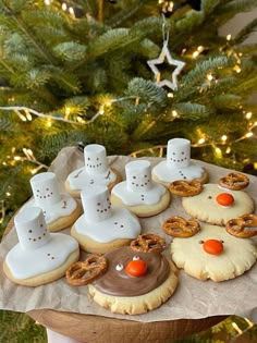 decorated cookies and pretzels are on a tray in front of a christmas tree