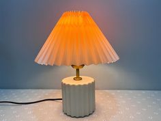 a lamp that is sitting on top of a white table with a blue wall in the background