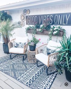 two wicker chairs sitting on top of a black and white rug next to potted plants