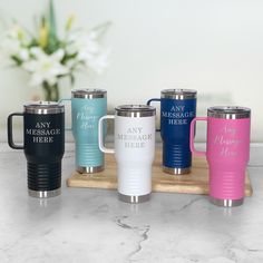 thermos mugs are lined up on a wooden tray