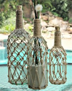 three vases with flowers in them sitting on a table next to a swimming pool