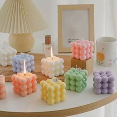 there are many small candles on the table next to a candle holder and a cup