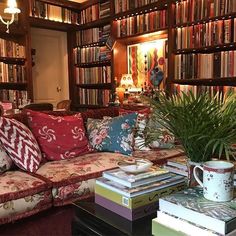 a living room filled with lots of furniture and bookshelves full of books on top of them