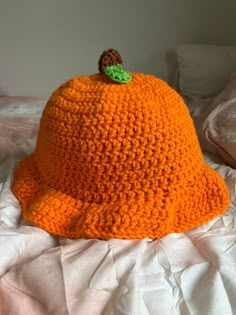 an orange crocheted hat sitting on top of a bed