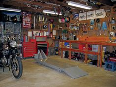 a garage filled with lots of tools and workbenches on the wall, along with two motorcycles