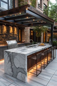 an outdoor kitchen with marble counter tops and bar stools