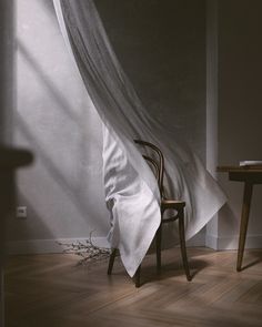 a chair sitting in front of a white curtain