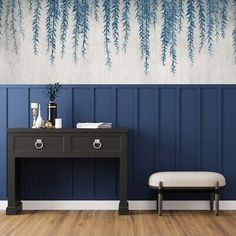 a blue and white room with a table, bench and plant on the wall next to it