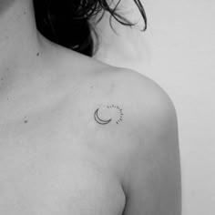 a black and white photo of a woman's chest with a crescent tattoo on it