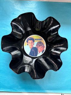 a black plastic bowl with two people on it's side and one is in the shape of a flower