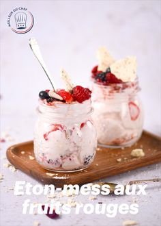 two mason jars filled with fruit on top of a wooden tray next to a spoon