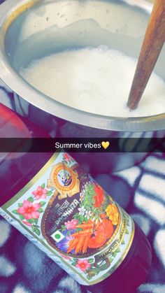 a bottle of beer sitting in front of a pot filled with liquid and a wooden spoon