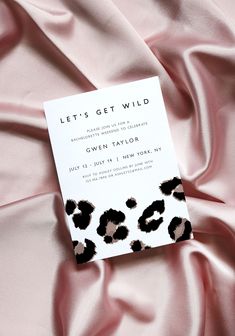 a card that is laying on top of a pink sheet with black and white animal print