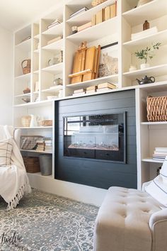 a living room filled with lots of white furniture and bookshelves above a fire place