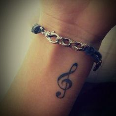 a person with a tattoo on their arm has a musical note tattooed on the wrist