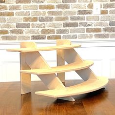 a wooden shelf sitting on top of a hard wood floor next to a brick wall