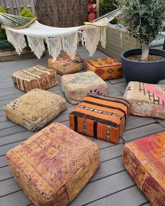 several different colored ottomans on a deck with a hammock hanging in the background