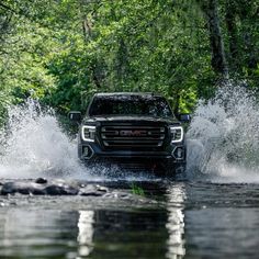 a black truck driving through a river filled with water