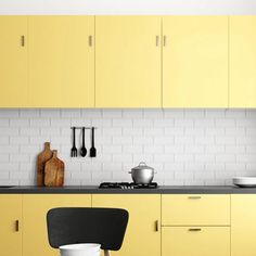 a kitchen with yellow cabinets and black counter tops is pictured in this image, there are two chairs next to the stove