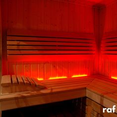 the inside of a sauna with red light coming from it's sides and two benches