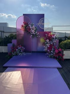 an outdoor stage set up with flowers on the side and purple carpeted flooring