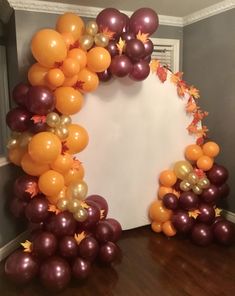 an arch made out of balloons and fall leaves