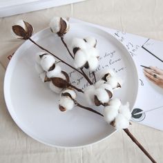 cotton flowers on a white plate next to an envelope